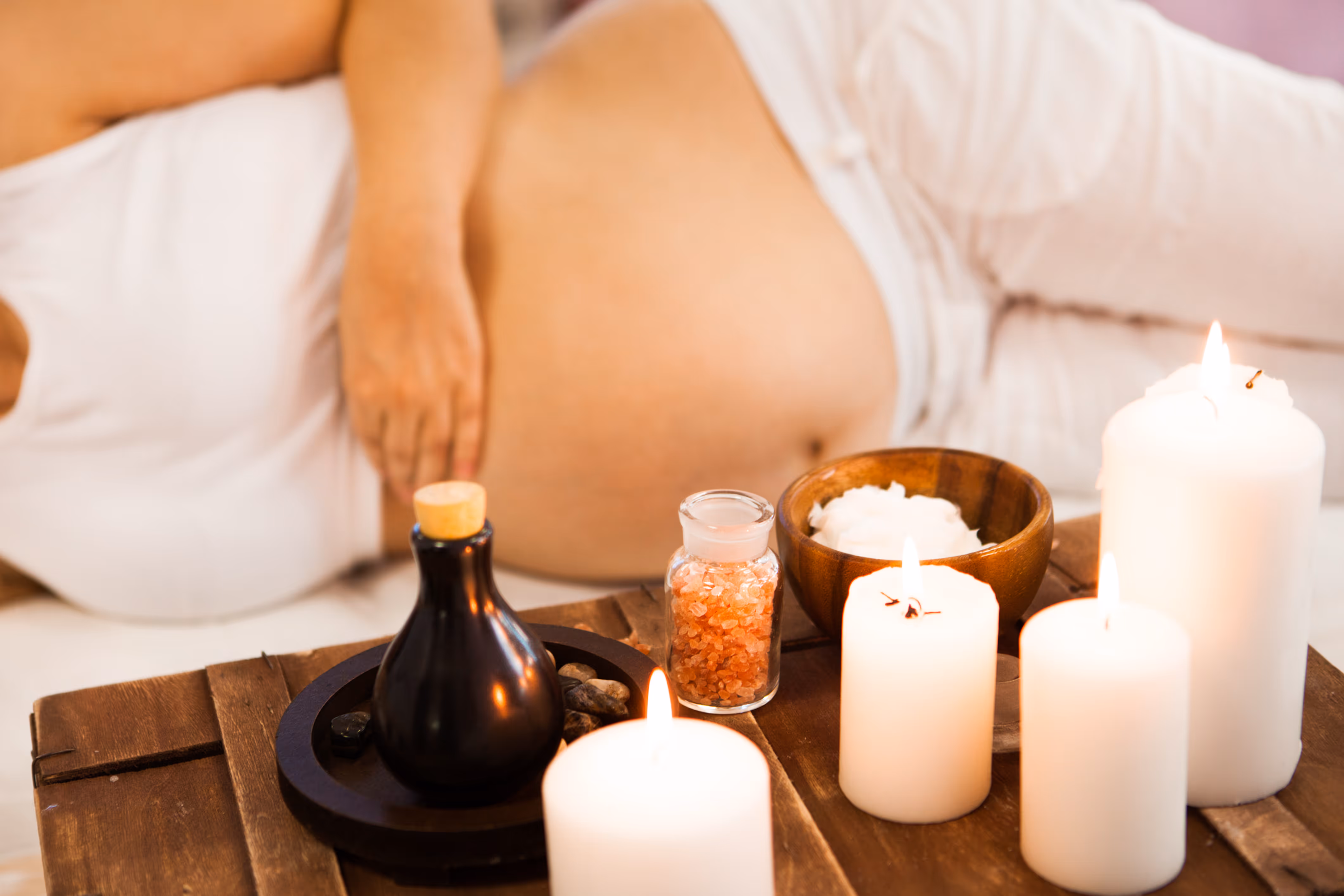 Pregnant Woman being massaged, with flowers and oil in foreground